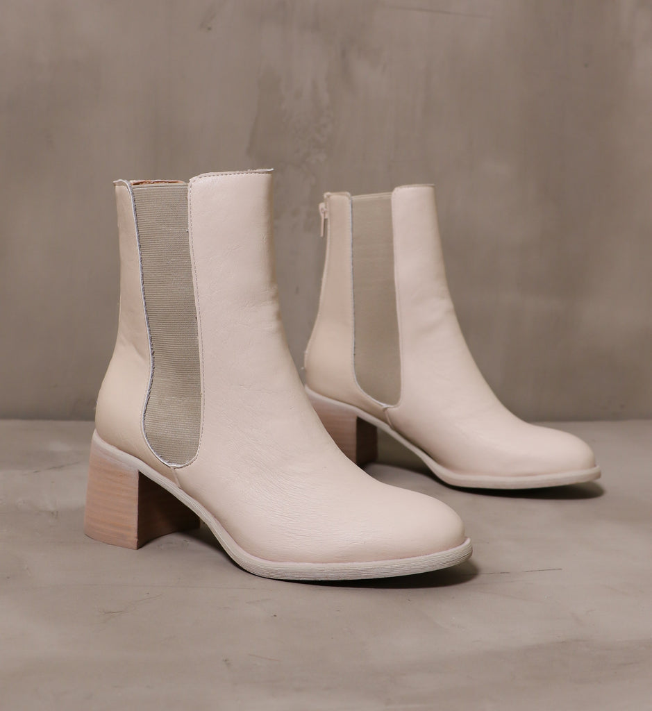 pair of off white leather block heel consider it done boots on cement background