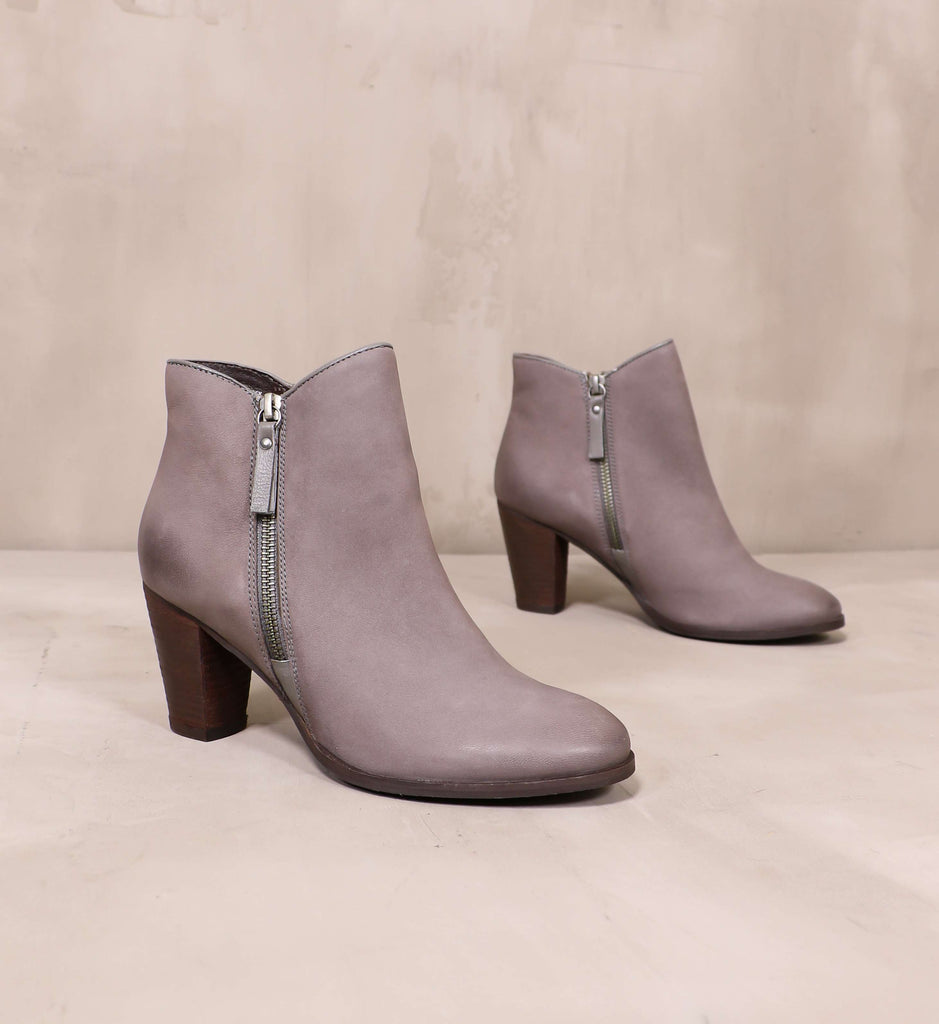 pair of grey leather heart zips a beat booties angled on cement background