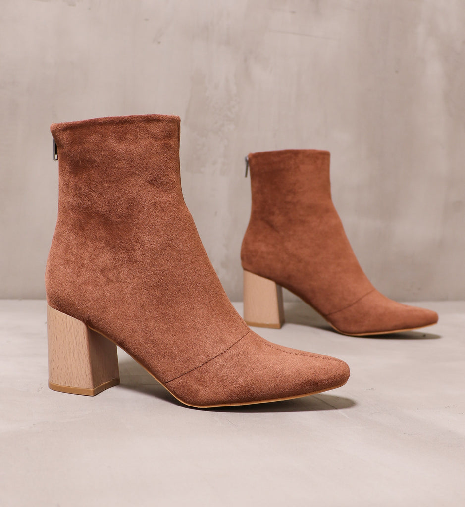 pair of chestnut brown suede boots angled on cement background