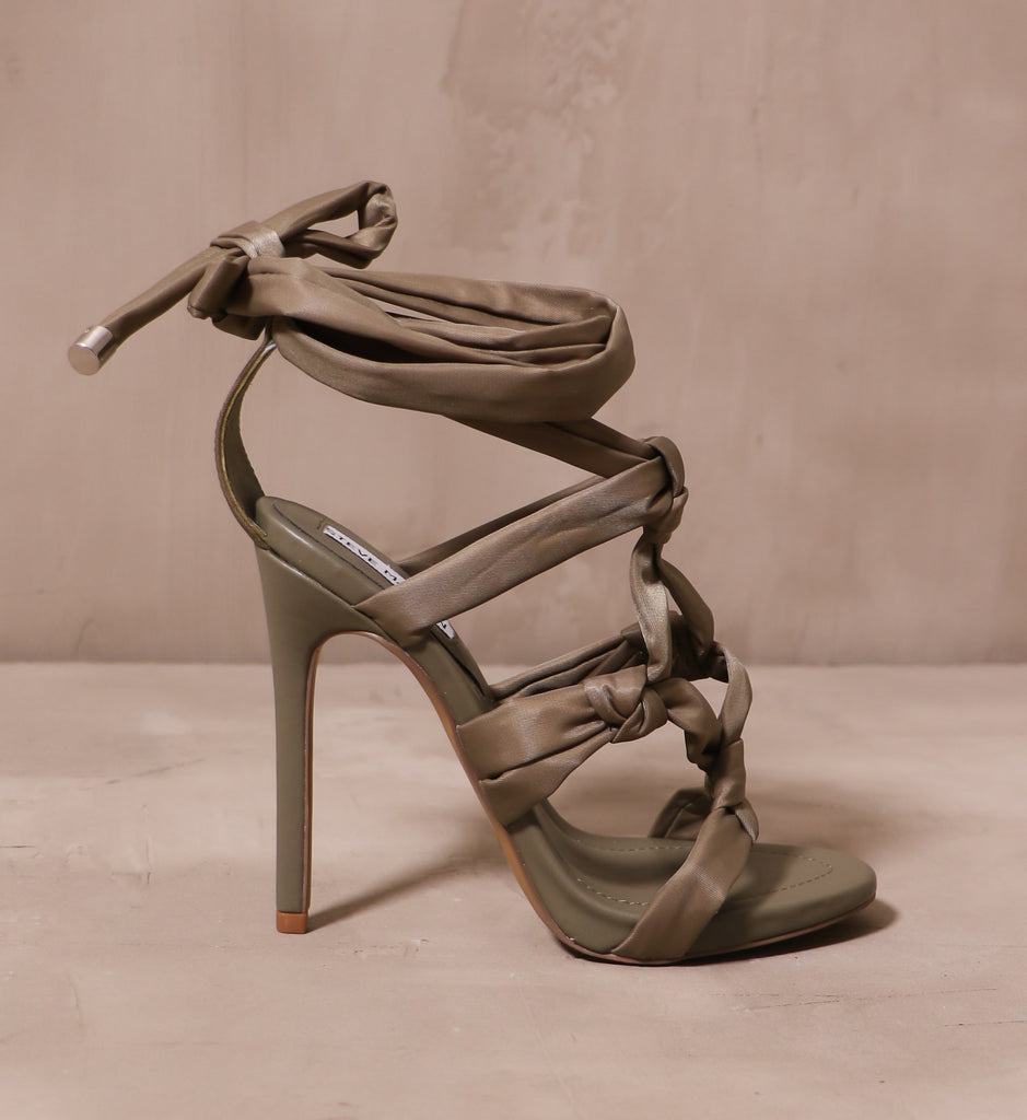 outer side of the green fabric straps on the tall thin sole of the olive you forever heel 