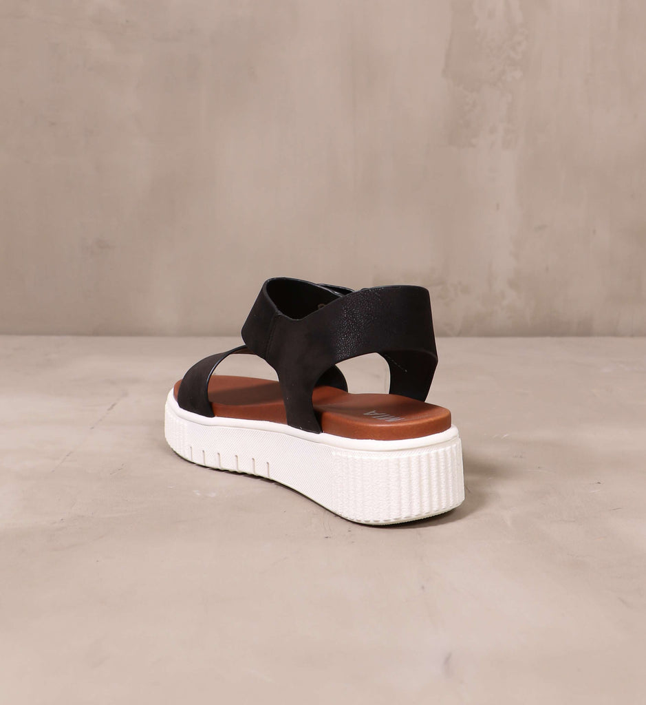 back of the white chunky rubber platform sole and black straps