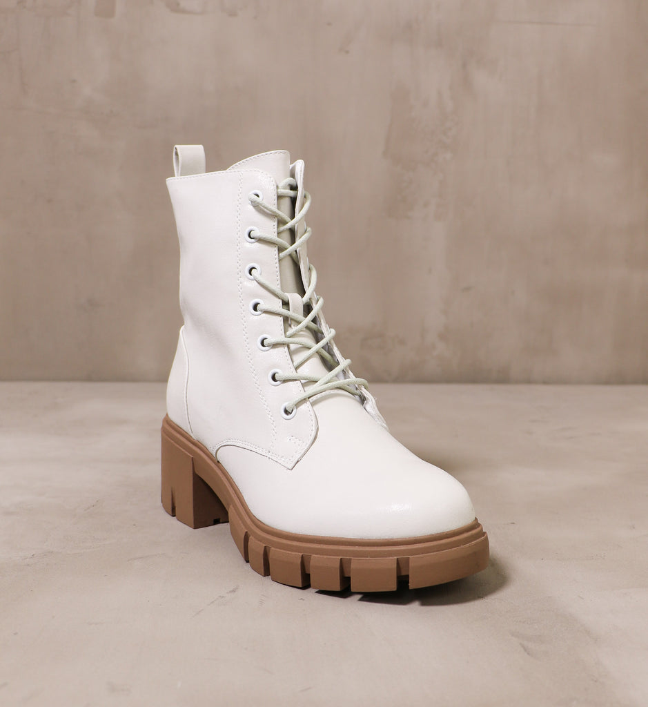 front of the round toe speed of white leather boots with chunky brown lug sole