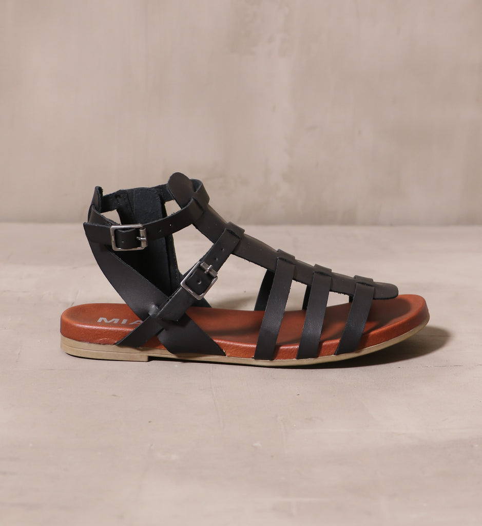 outer side of the black strappy makes me happy cage sandals with brown insole and taupe tread