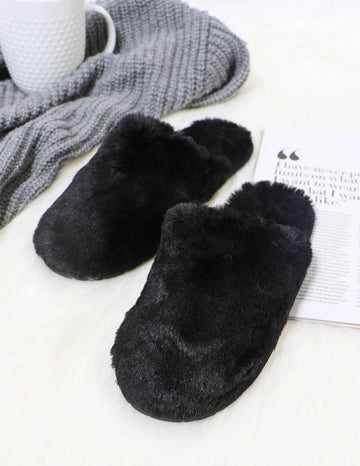 Black fuzzy wuzzy slipper in black on a white rug