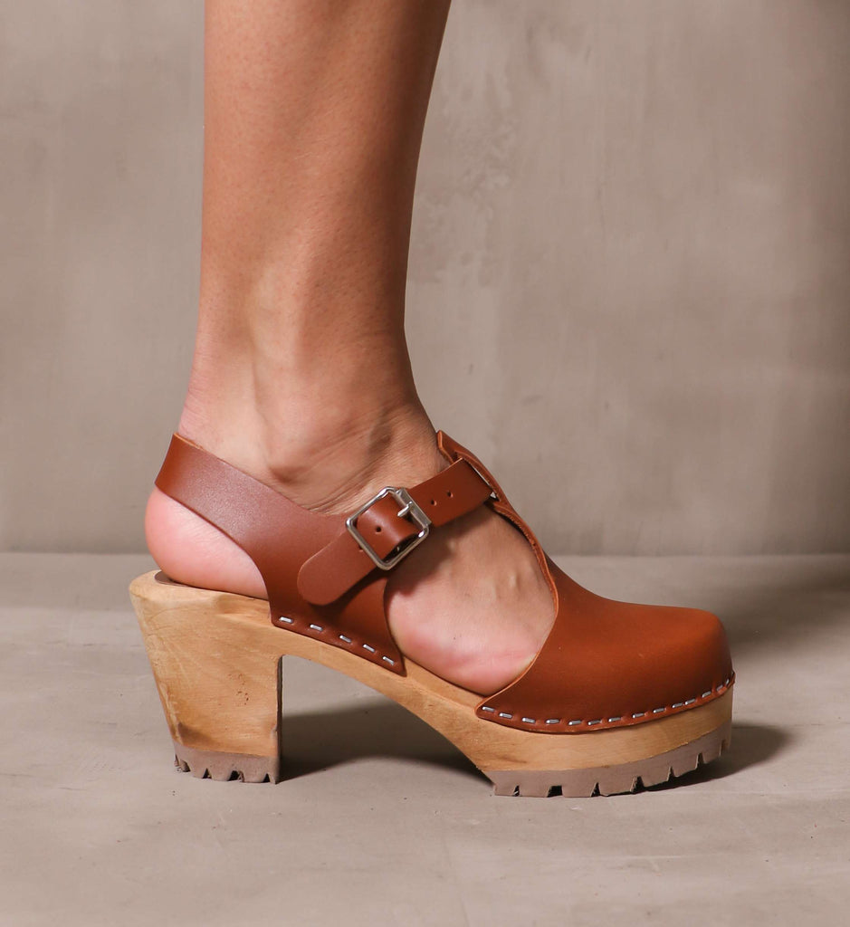outer side of the brown leather madeline t strap clog on model 