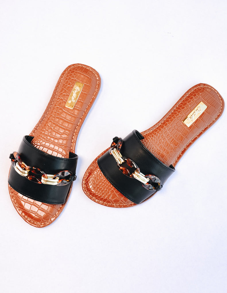 Top view of black and tan slides on white background - elle bleu shoes