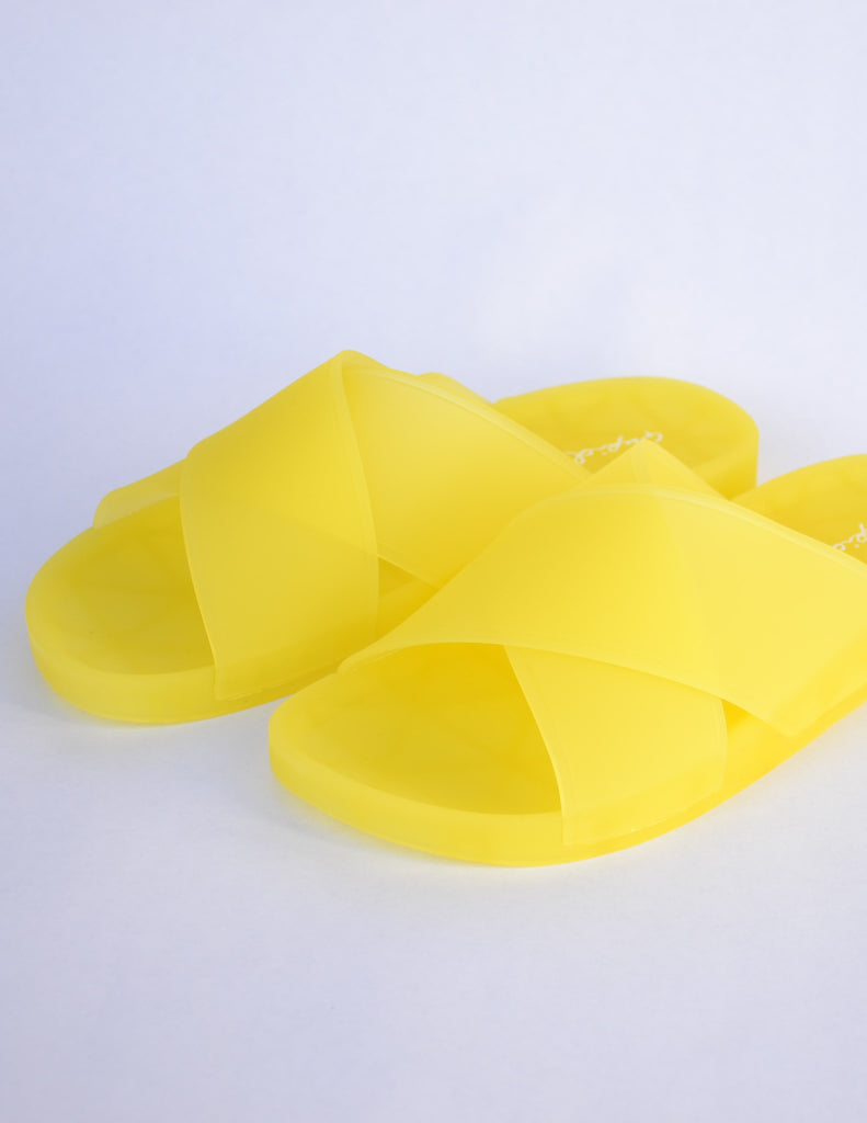 Yellow slide sandals with thick crossing straps over the top of the shoe