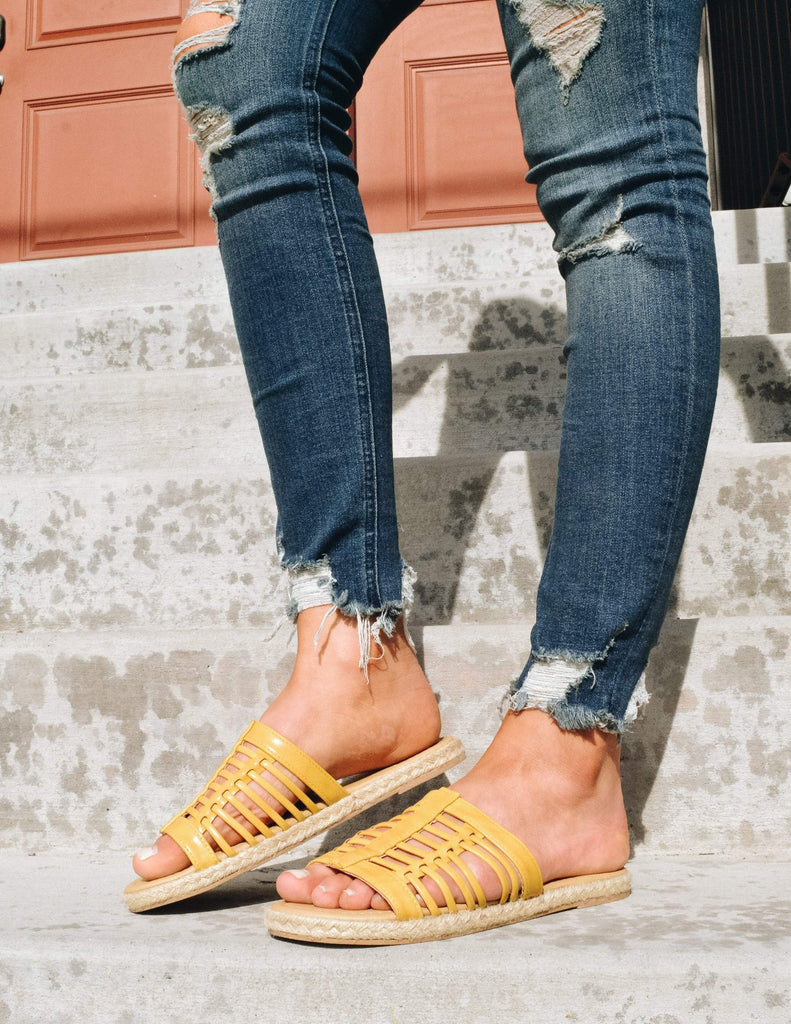 Knee down shot of model standing in denim and yellow surf's up sandal