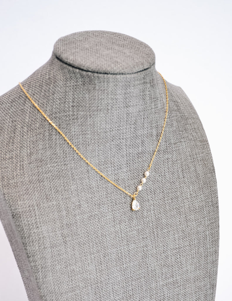 Gold caprie necklace on form showing crystal pendant and pearls