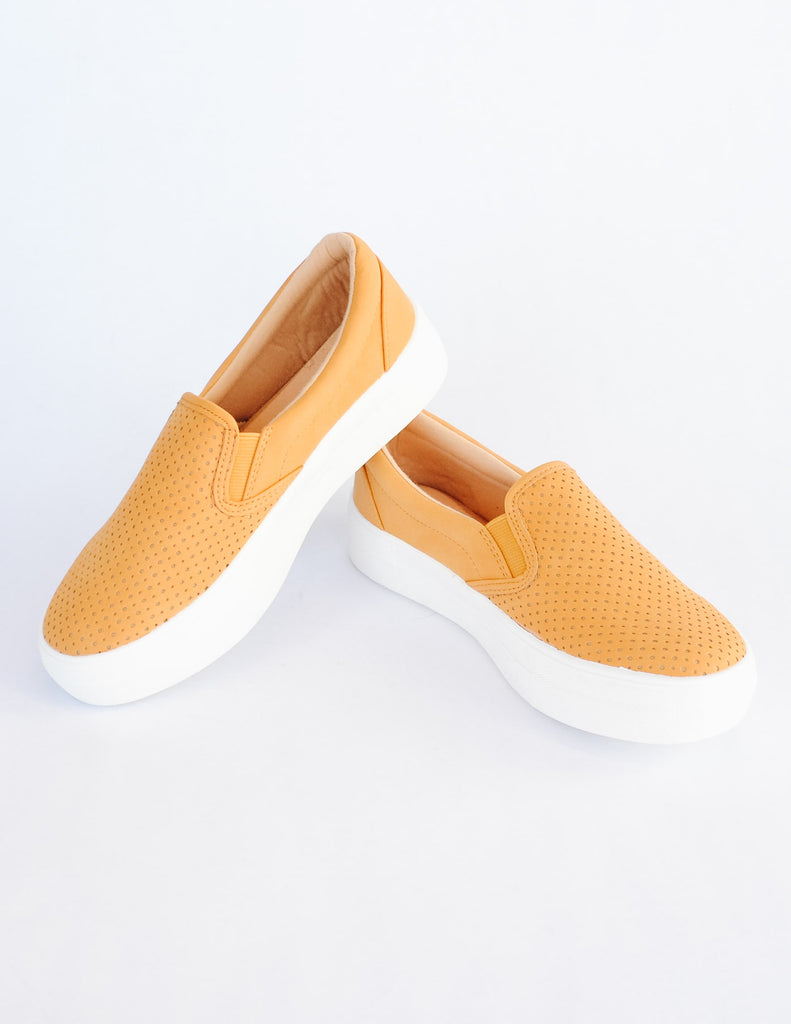 Yellow mango colored perforated slip on sneaker with thick white sole