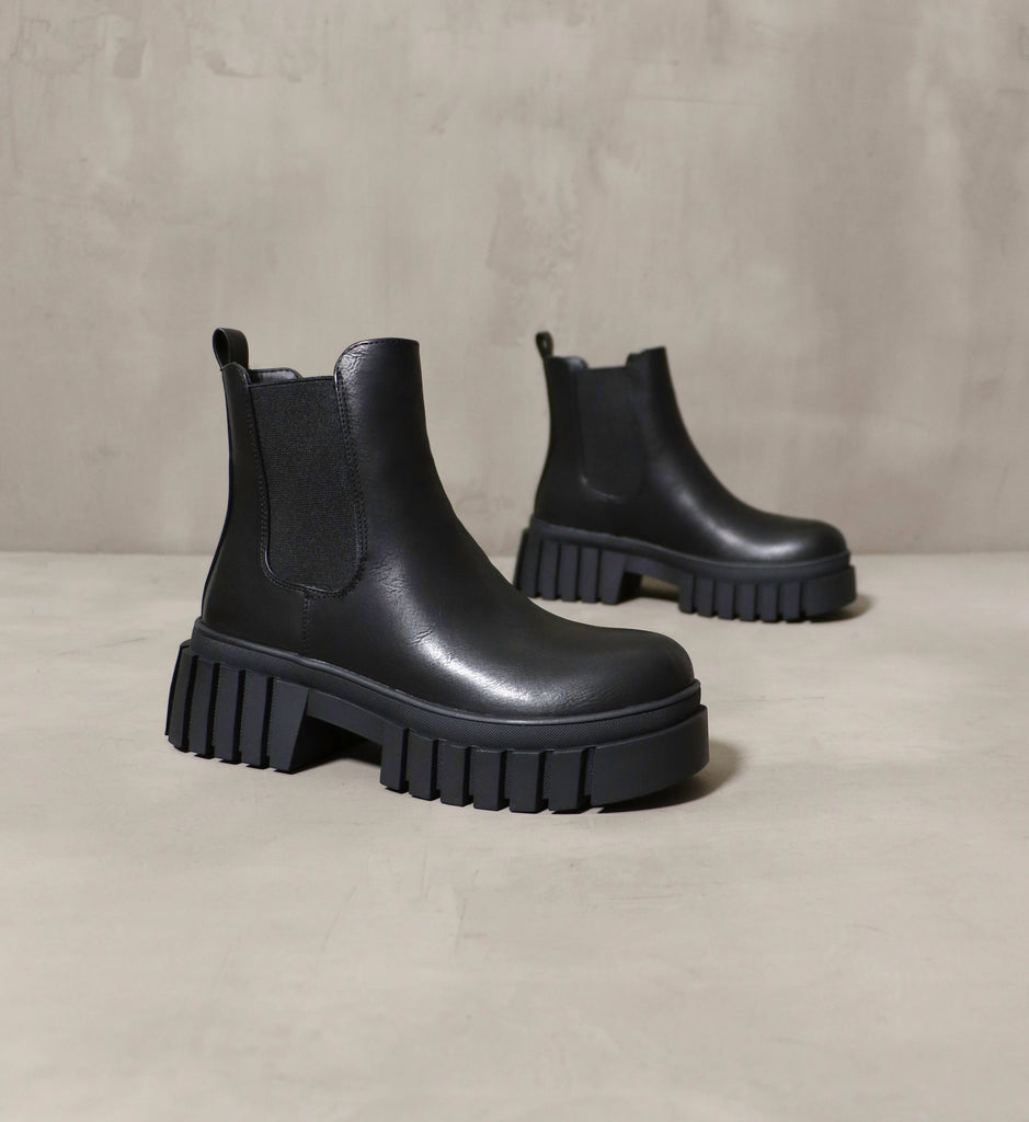 Black chunky sole ankle boot on a cement backdrop - Elle Bleu