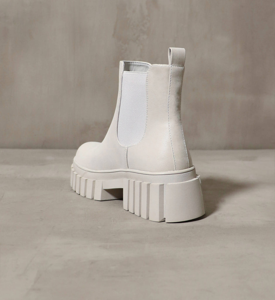 The heel view of the Never A Sole Moment ankle boot on a cement backdrop - Elle Bleu