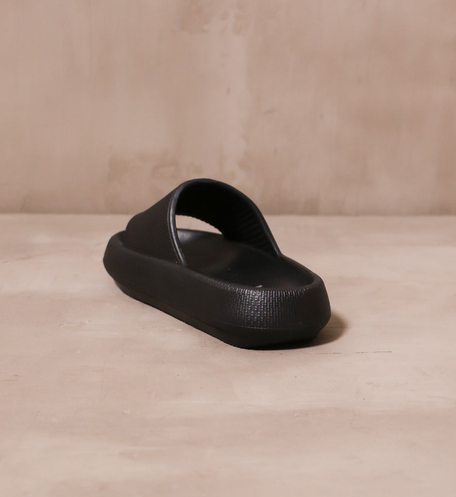 back of the open toe black late to the foam party slide sandal on concrete background