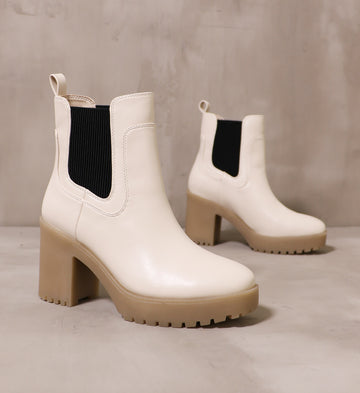pair of off white chelsea you around boots with brown chunky soles angled on cement background