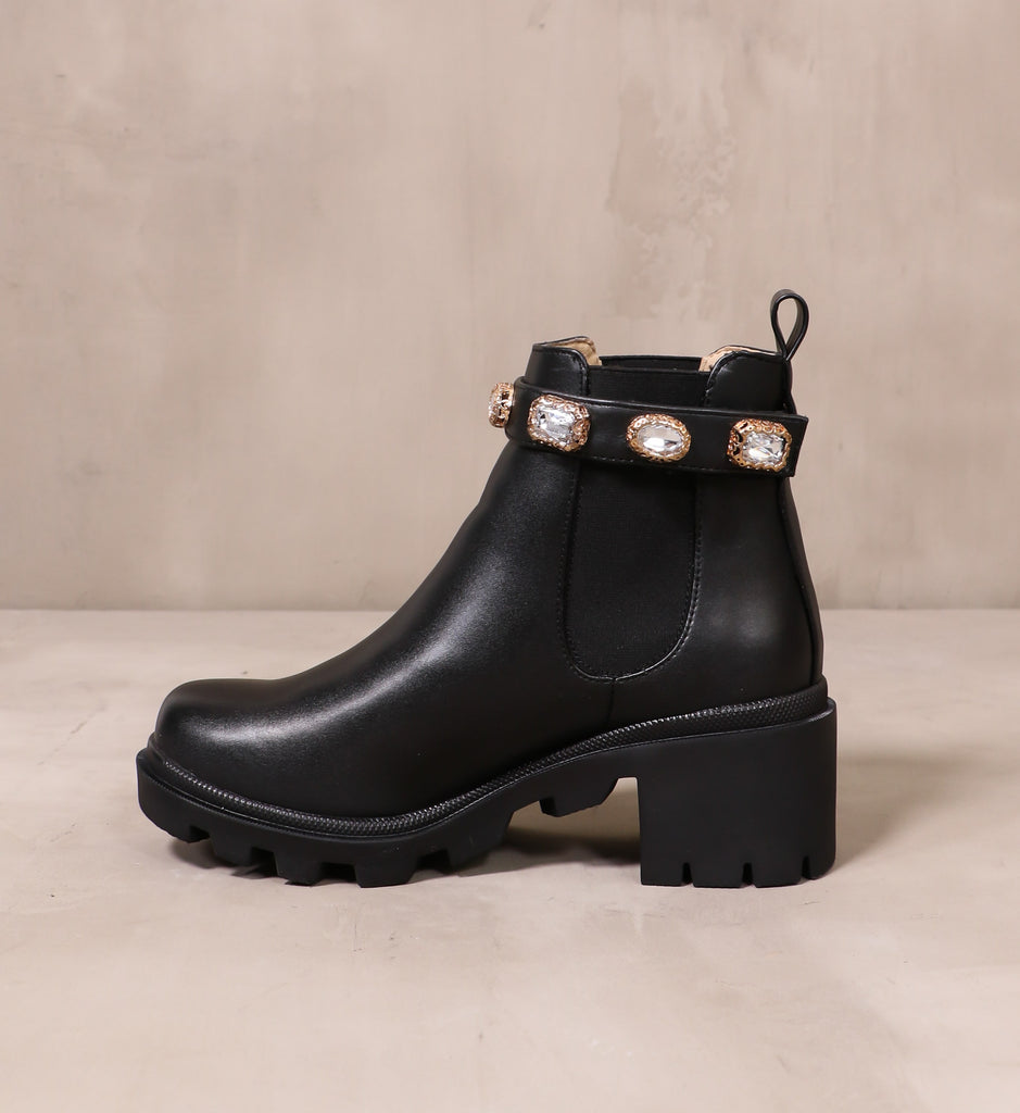 inner side of the all black drip'in diamonds boot with chunky rubber lug sole on cement background