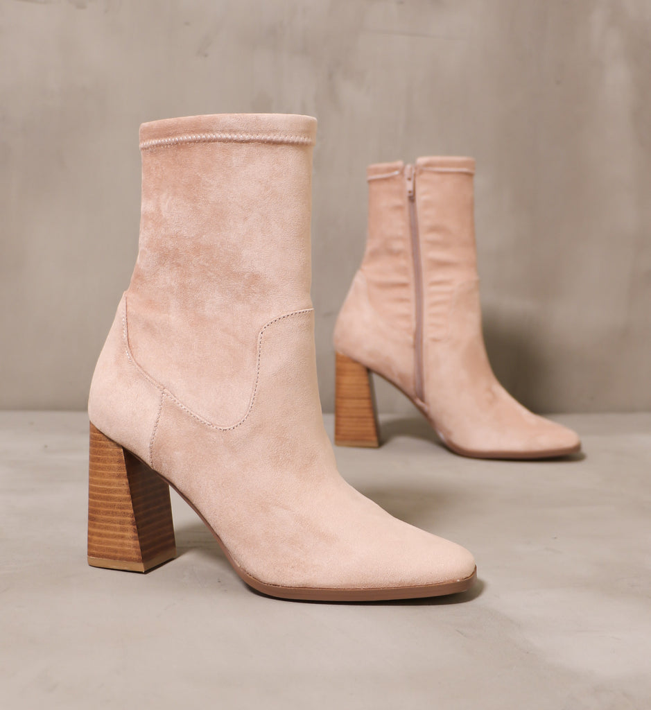 pair of the forget yesterday boots with blush pink suede upper and stacked wood block heels angled on cement background