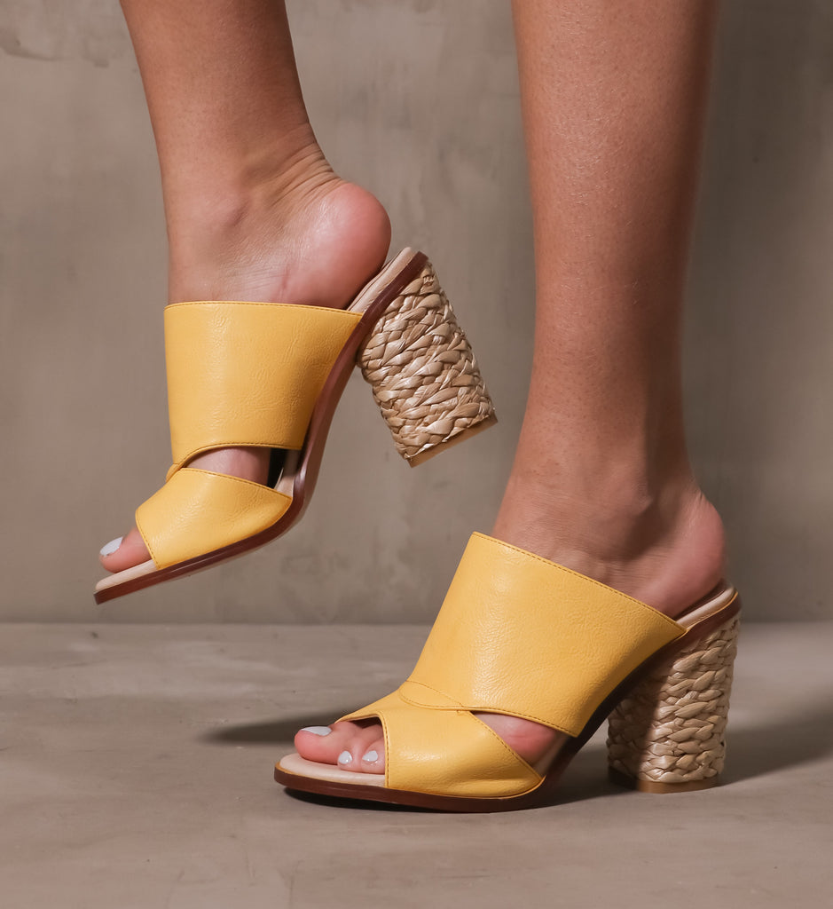 model standing in the hello yellow block open toe heels on cement background