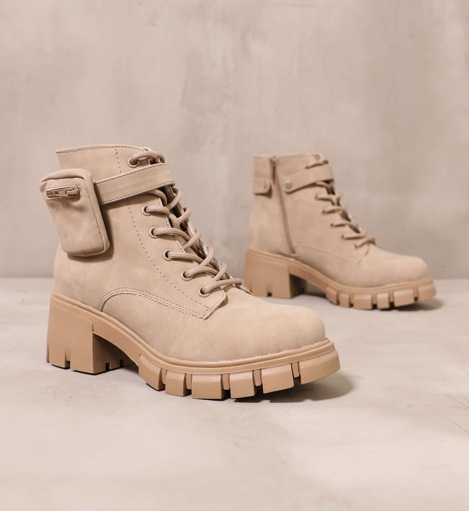 pair of taupe it's not pocket science boots angled on cement background