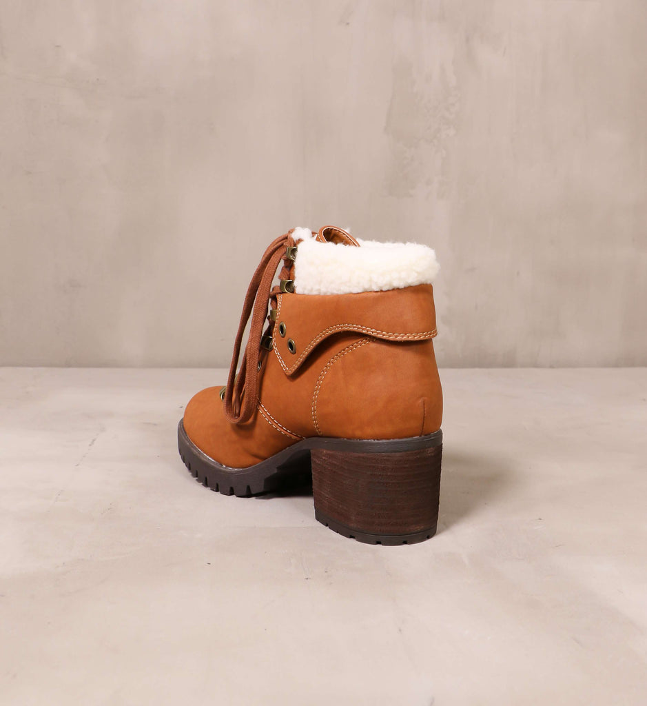 back of the stacked wood heel on the keep me cozy boot with luggage tan brown leather upper and sherpa trim on top