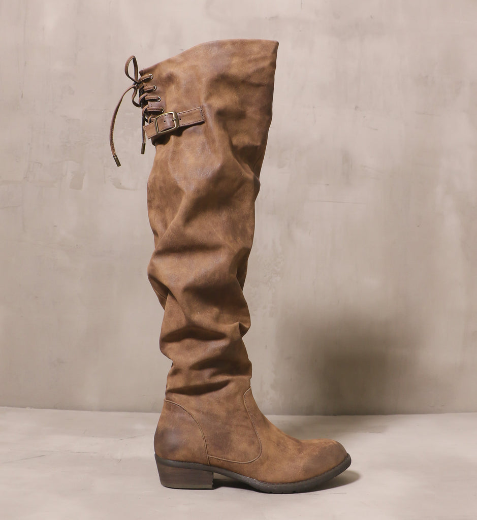 outer side of the I knee'd a coffee boot with distressed leather upper with slouchy silhouette and back buckle strap on the back of the knee