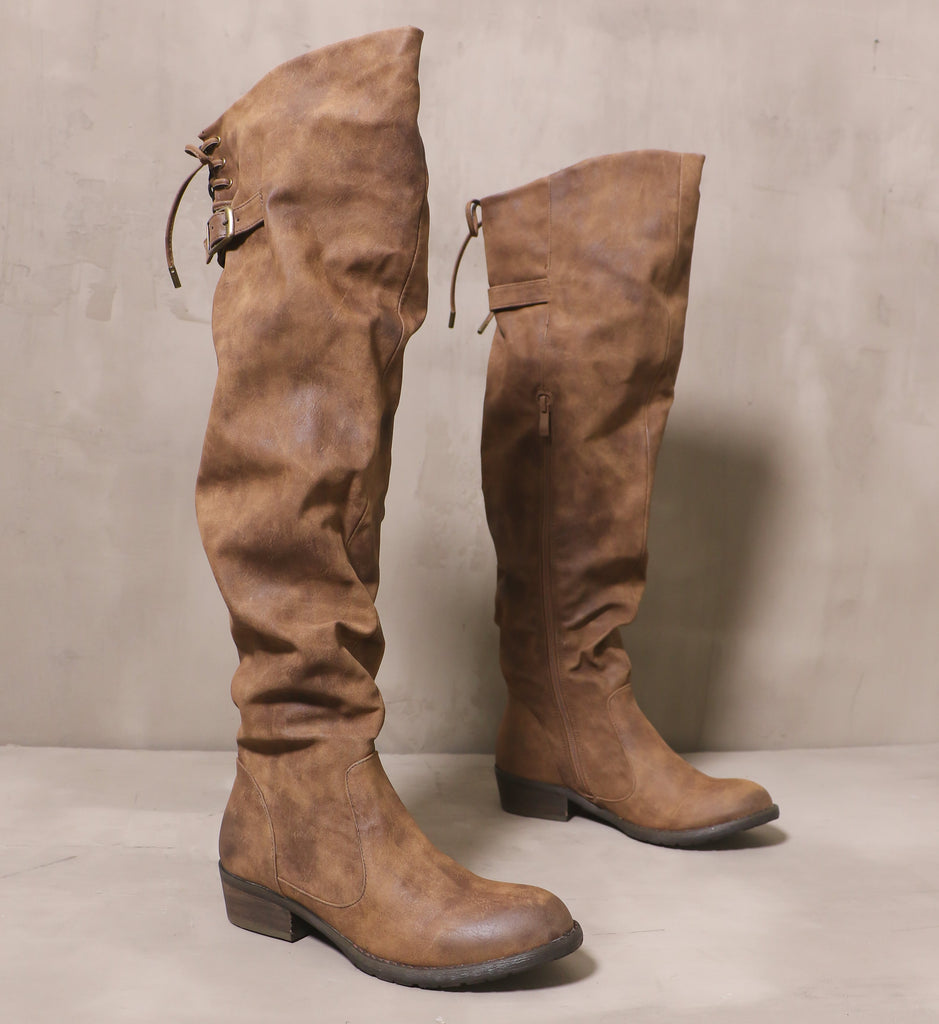 pair of I knee'd a drink brown tall knee high boots with distressed leather upper and brown sole on cement background