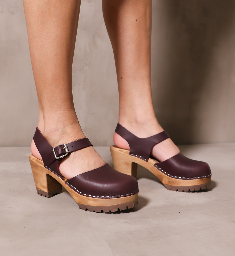 pair of the maroon abba swedish clogs on model on cement background
