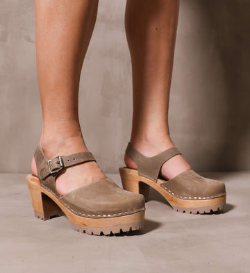 model wearing the taupe abba swedish clogs on cement background
