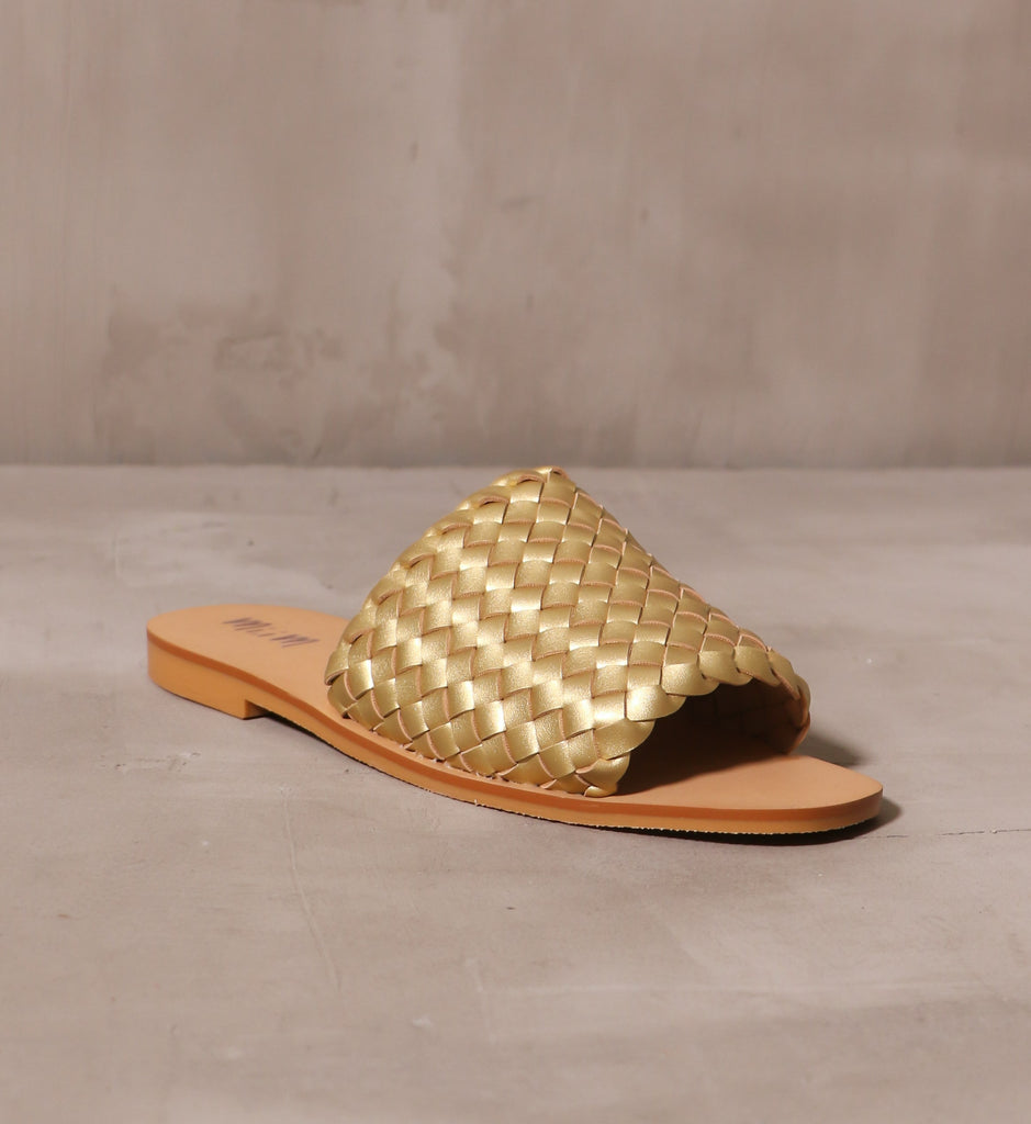 front of the open toe the woven one gold slide sandal on cement background