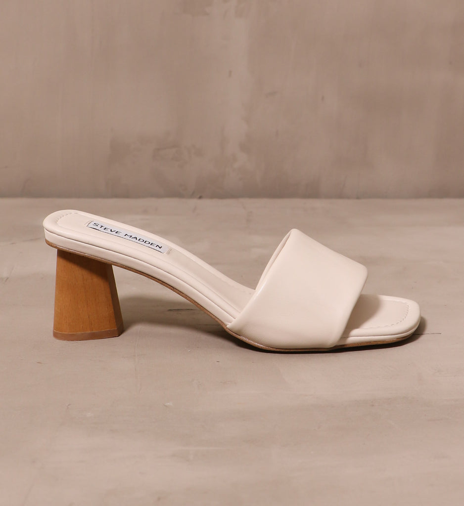 outer side of the cream modern kinda gal heel with tan wood heel on cement background