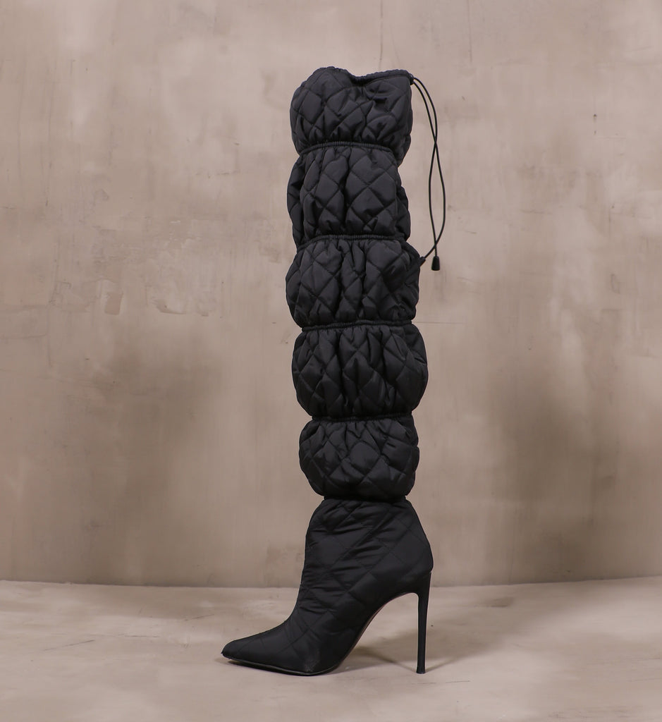 inner side of the mother puffer quilted boot with stiletto heel on cement background