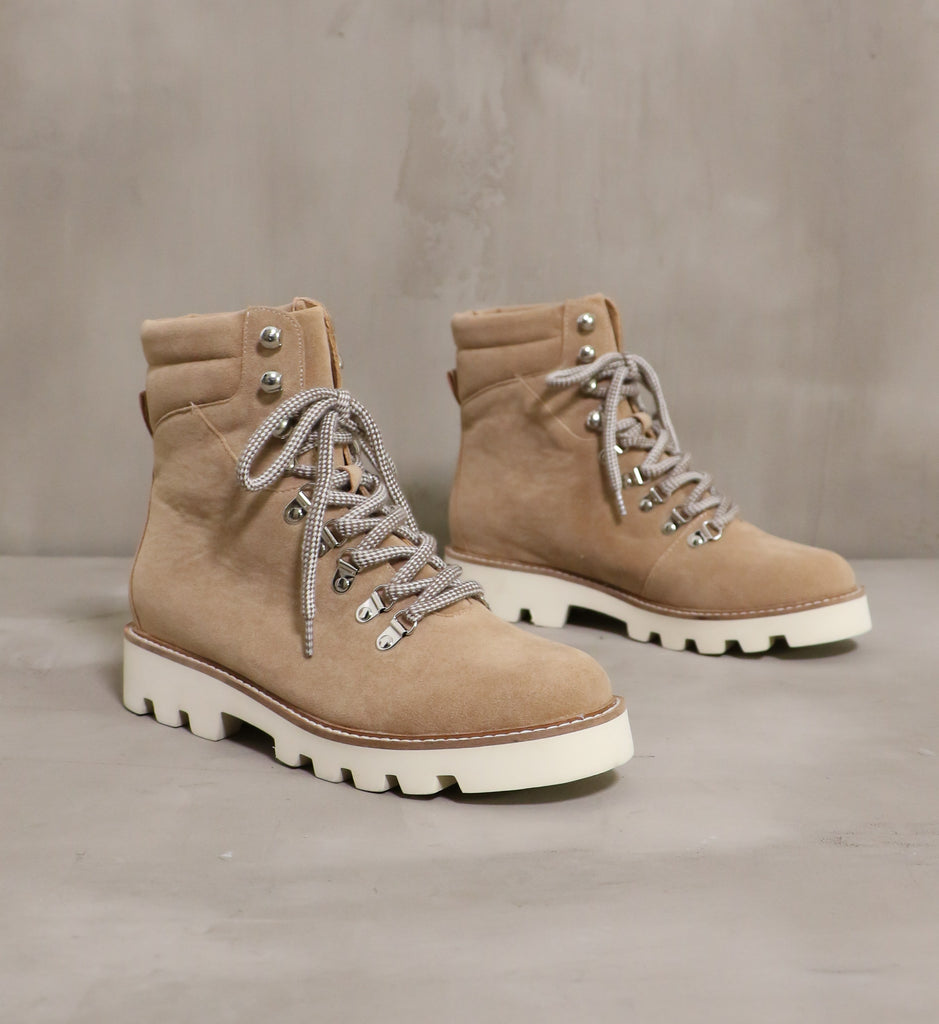 pair of khaki taupe brown neutral territory boots with cream lug soles on cement background