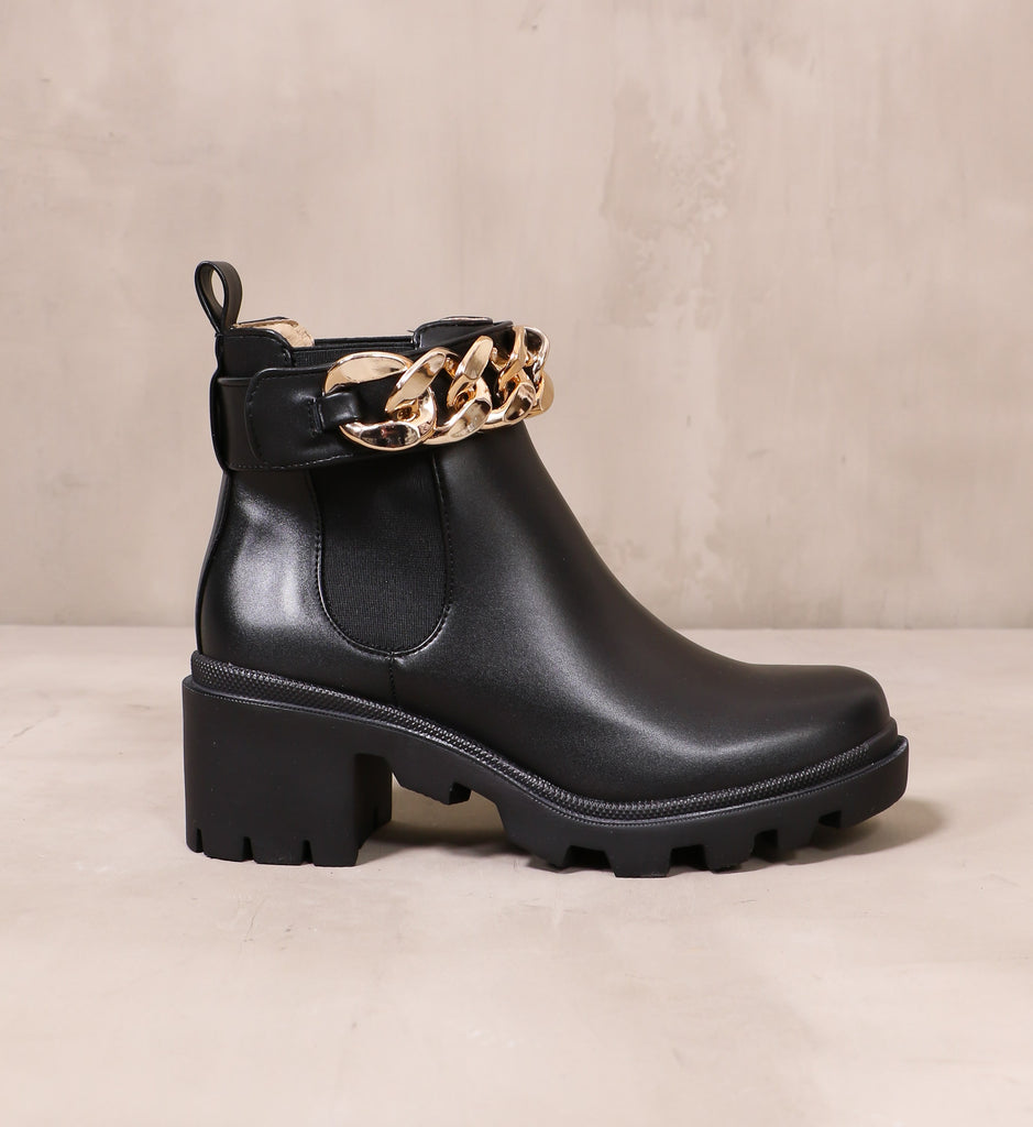 outer side of the black leather off the chain boot with gold chain detail around the top