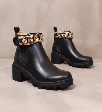 pair of all black off the chain lug sole boots angled on cement background