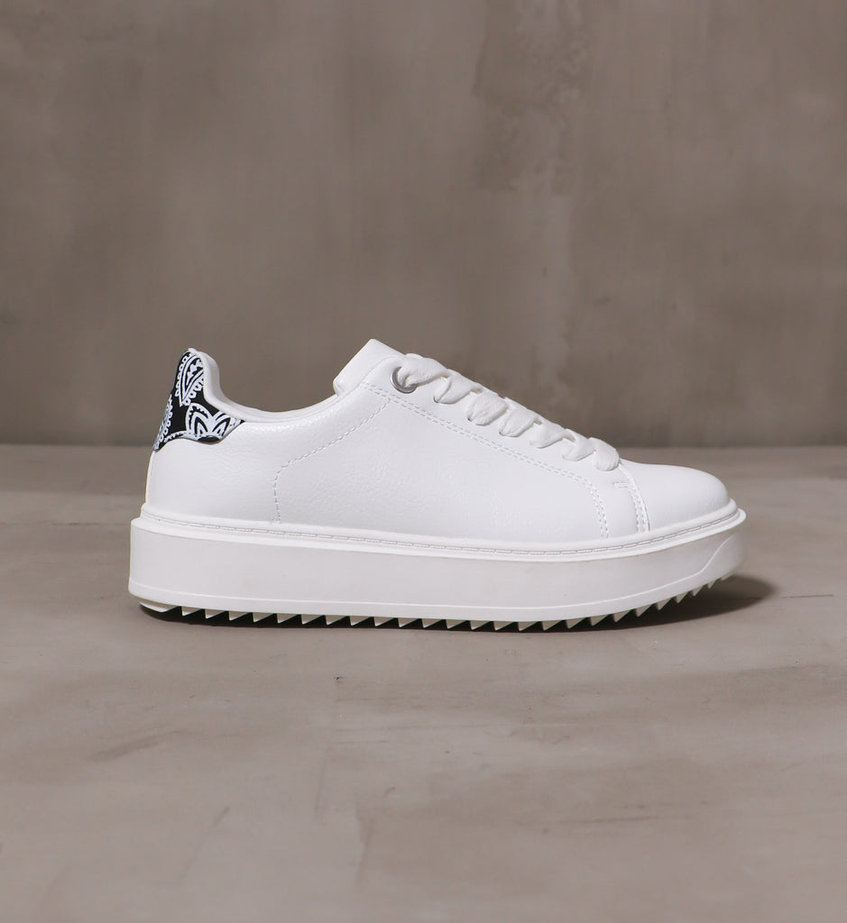 outer side of the white pais-lead the way sneaker with chunky rubber sole on cement background