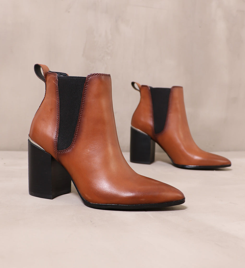 pair of cognac brown perfectly trimmed ankle boots angled on cement background