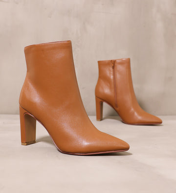 pair of brown tan leather sleek step ankle boots angled on cement background