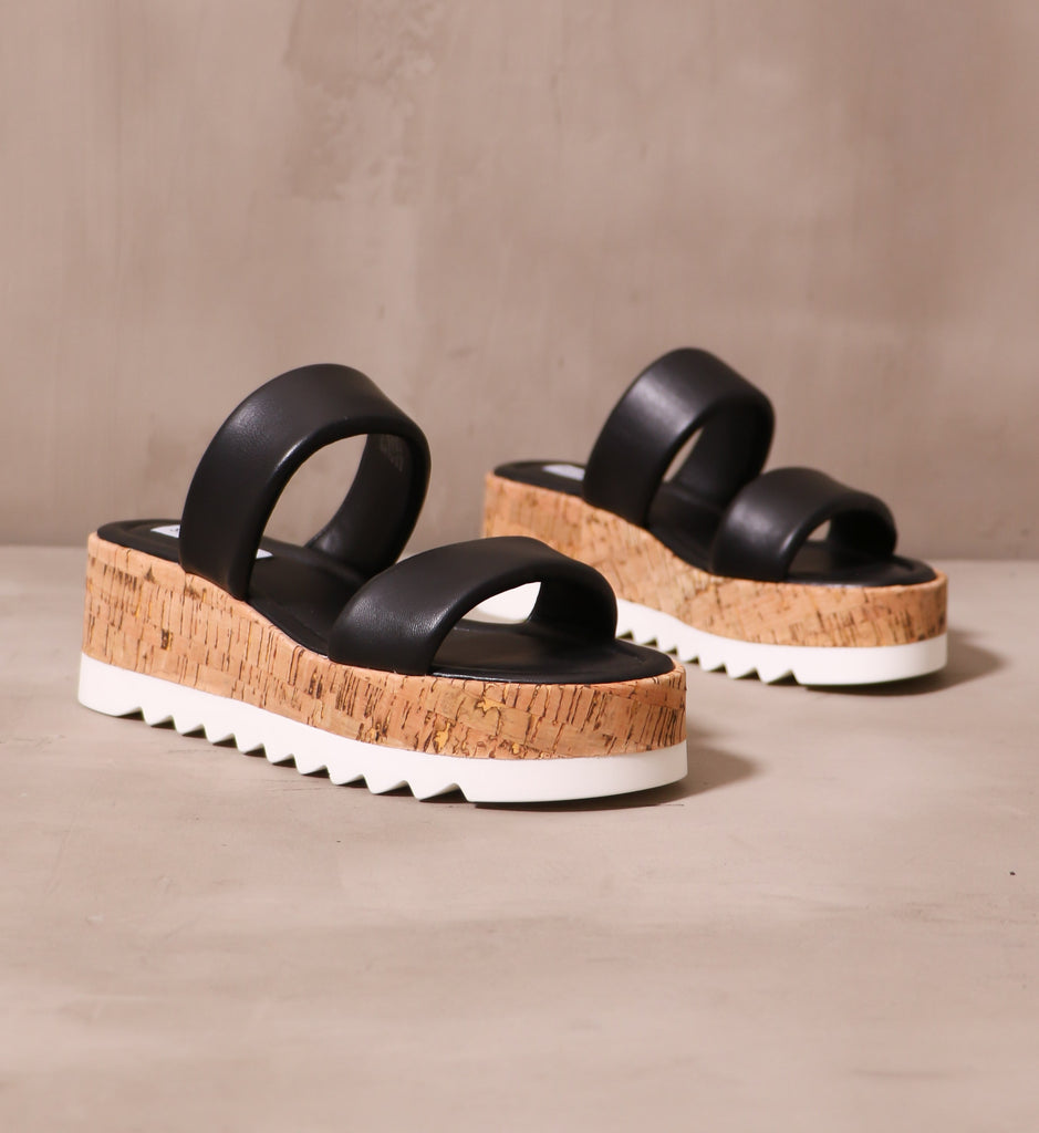black puffy leather straps on cork sole with chunky white tread on the sole purpose platform sandals