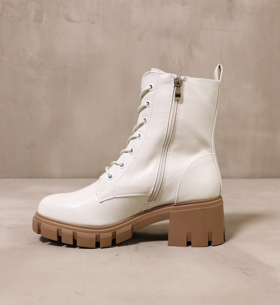 inner side of the speed of white boot with silver zipper pull and brown chunky rubber tread