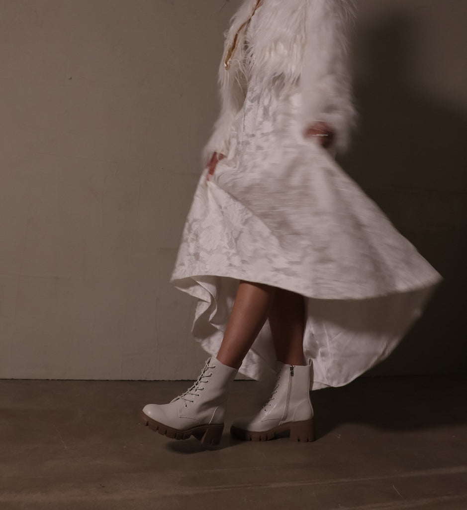 model walking in white lace dress, furry coat, and speed of white lug sole boots