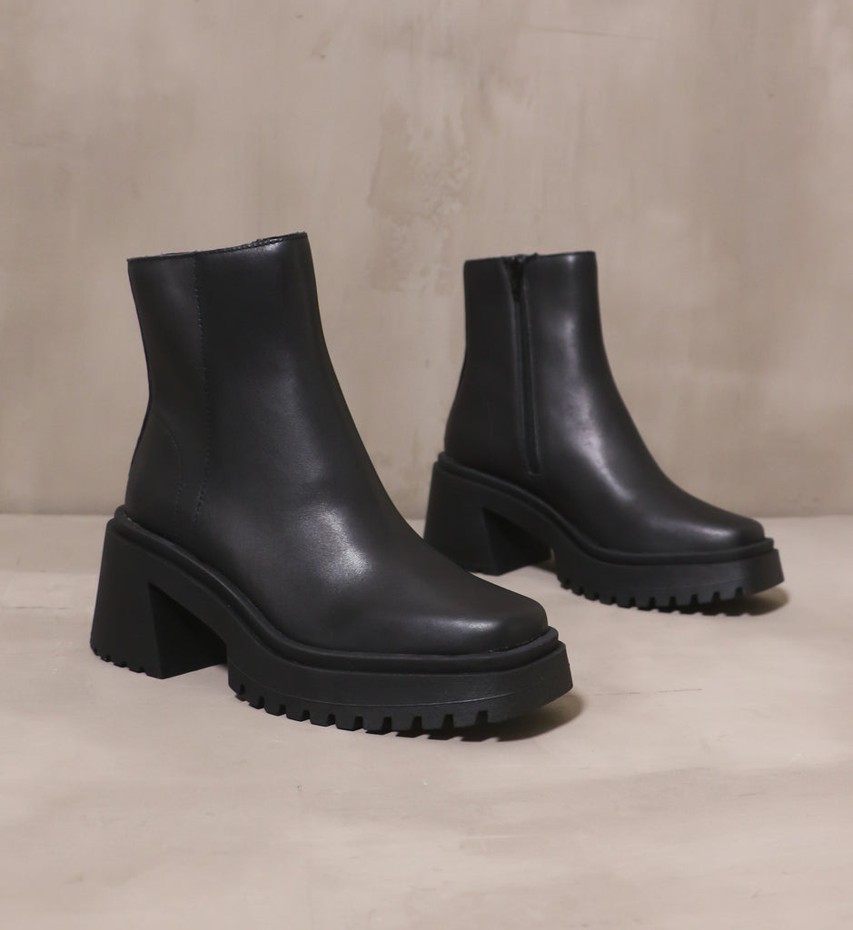 pair of chunky all black shadow of a doubt boots on cement background