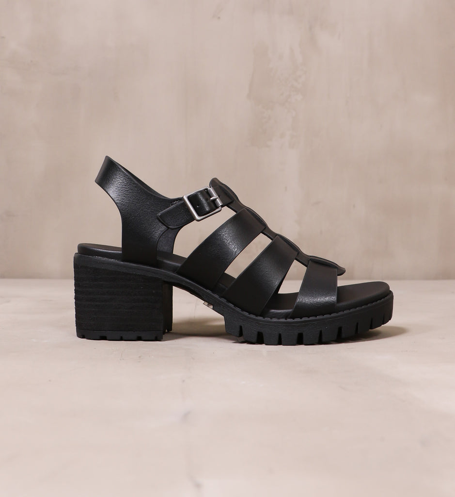 outer side of the all black strappy to cleat you platform sandal with silver buckle closure