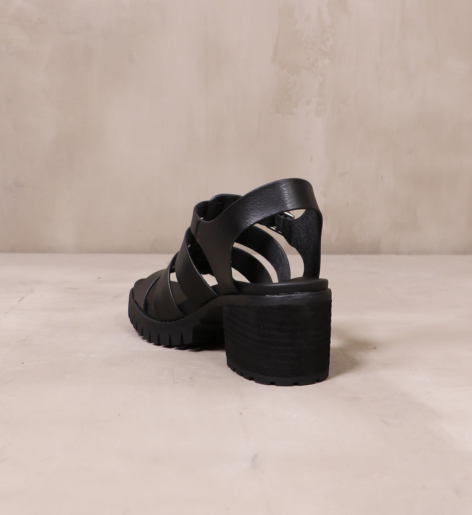 back of the black stacked wood heel on the strappy to cleat you sandal