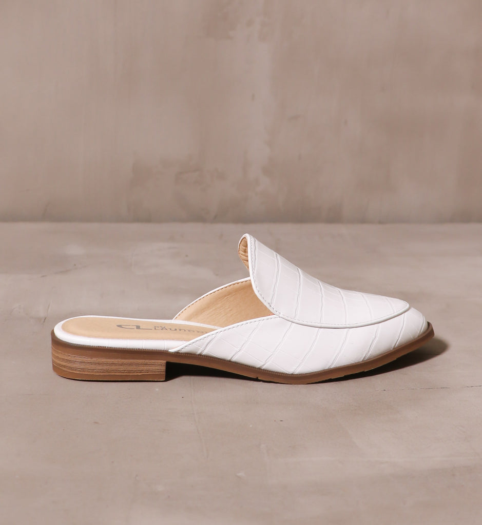 outer side of the slip on sugar and spice mule with shallow stacked wood heel on cement background