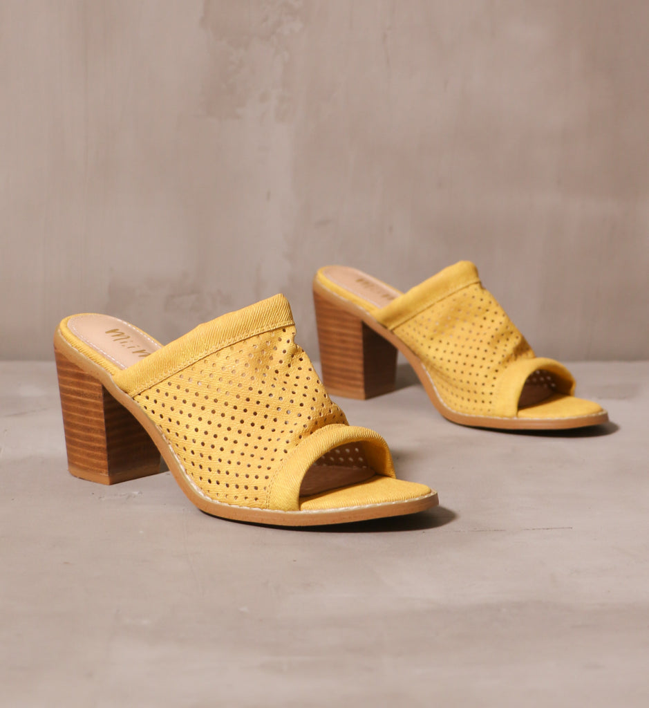 pair of yellow open toe sunshine state of mind block heels angled on cement background