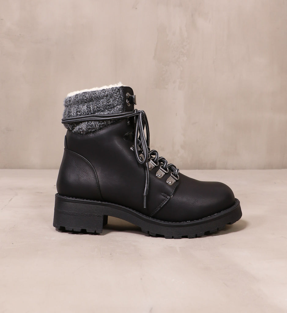 outer side of the black leather sweater together boots with chunky rubber lug sole on cement background