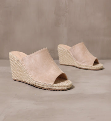 pair of talk to the sand beige wedges with espadrille rope wrapped sole on cement background