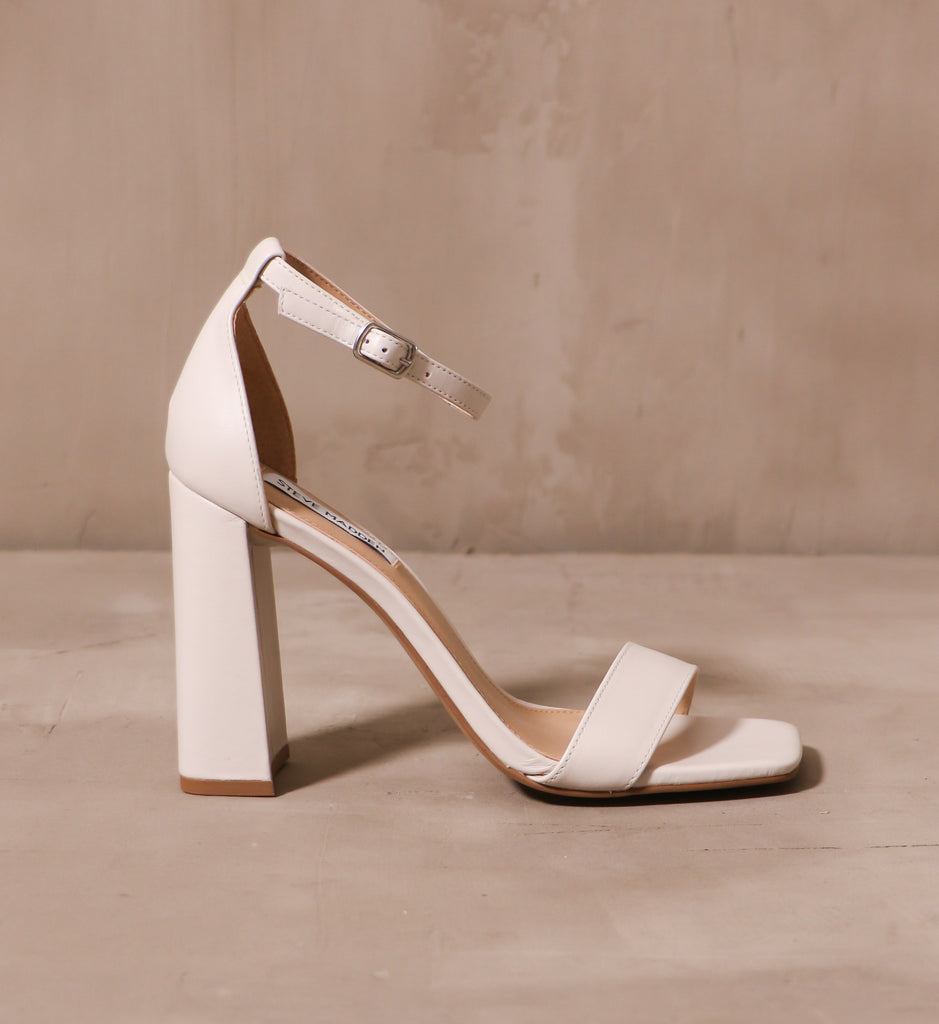 outer side of the off white steve madden there chic goes block heel on cement background