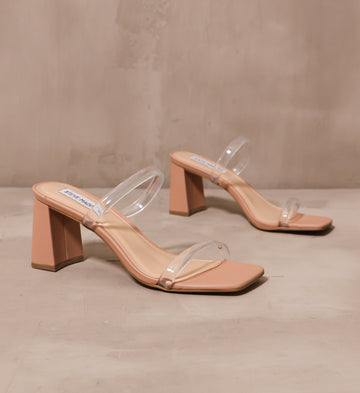 transparently timeless heel with thin clear rubber straps across the bridge and vamp with tan sole on cement background
