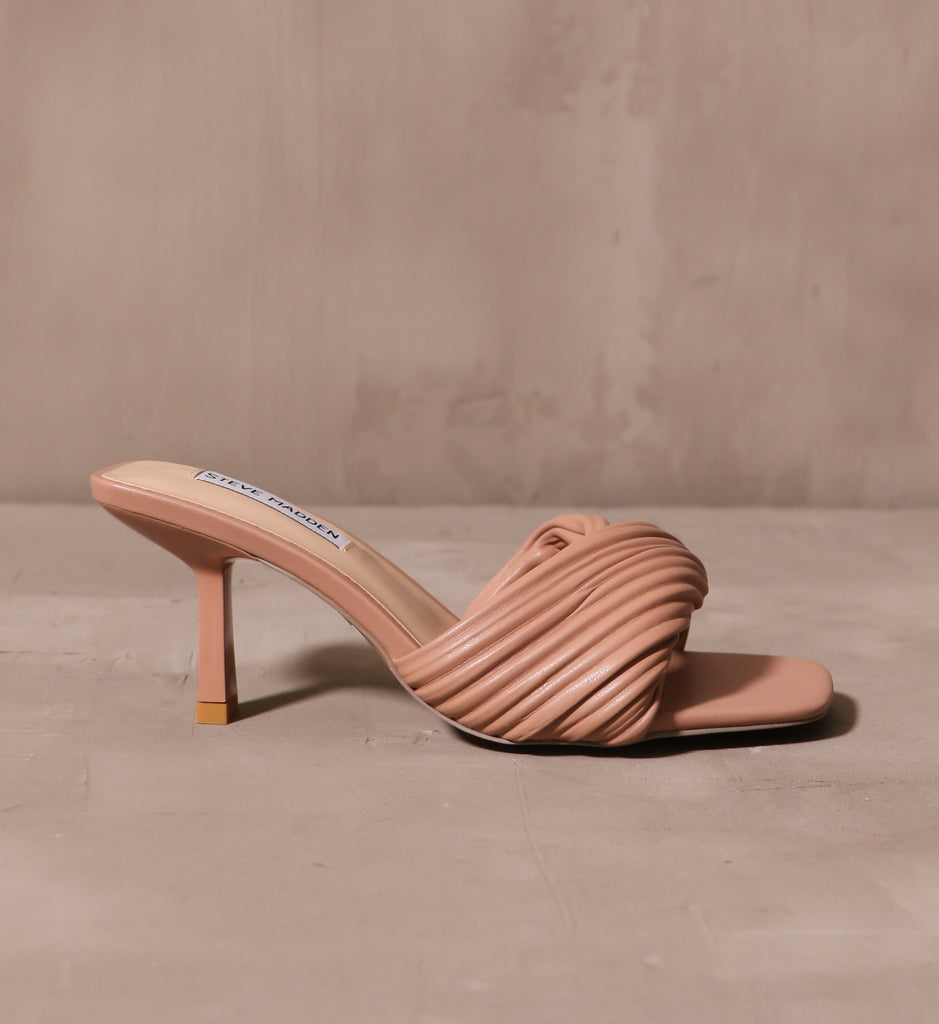 outer side of the twist of fate heel with curved stiletto heel on cement background