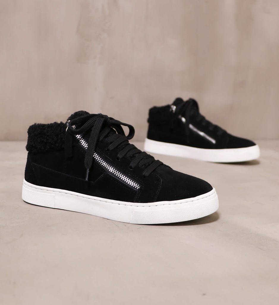 pair of black warm feelings sneakers angled on cement background